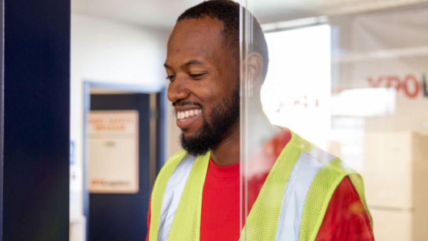 Benefits from the start A smiling XPO employee with a safety vest on