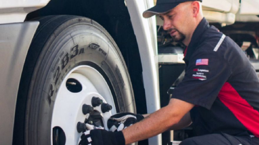 Safety first An employee with a hat on is working on the tire of a truck