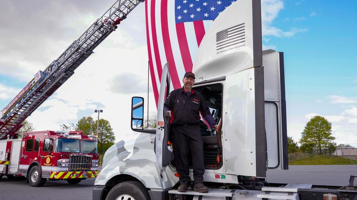 XPO Joins PaYS Driver in front of Military wrapped truck